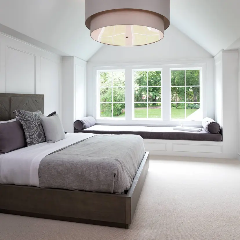 Bright bedroom with a large window seat and garden view.